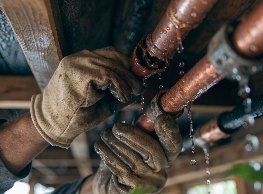 Plumber repairing a burst copper pipe